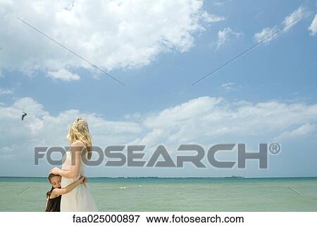 Mother and daughter hugging, ocean in background View Large Photo Image Stock Photo - Mother and daughter hugging, ocean in background. Fotosearch