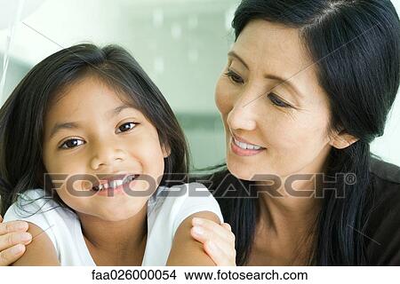 Mother and daughter smiling together, girl looking at camera View Large Photo Image Picture - Mother and daughter smiling together, girl looking at camera. Fotosearch