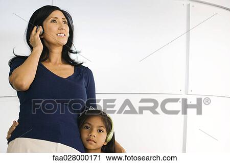 Mother and daughter standing side by side, listening to headphones View Large Photo Image Stock Image - Mother and daughter standing side by side, listening to headphones. Fotosearch