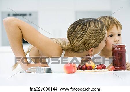 Mother and son preparing food together, boy holding apple, both looking down View Large Photo Image Picture - Mother and son preparing food together, boy holding apple, both looking down. Fotosearch