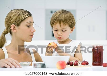 Mother and son preparing food together, boy holding apple, both looking down View Large Photo Image Stock Image - Mother and son preparing food together, boy holding apple, both looking down. Fotosearch