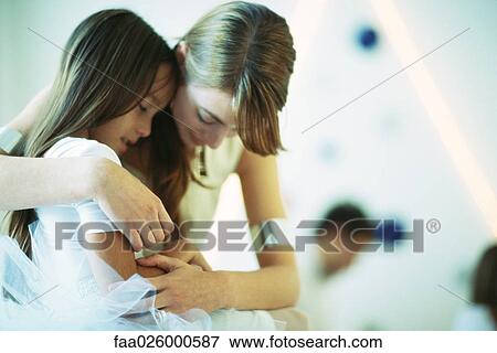 Mother embracing daughter, both looking down, close-up View Large Photo Image Stock Photo - Mother embracing daughter, both looking down, close-up. Fotosearch