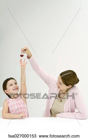 Mother holding up cherries, daughter reaching, both smiling View Large Photo Image Stock Image - Mother holding up cherries, daughter reaching, both smiling. Fotosearch