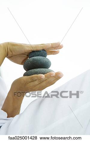 Person holding stacked pebbles in hands, cropped view View Large Photo Image Stock Photo - Person holding stacked pebbles in hands, cropped view. Fotosearch