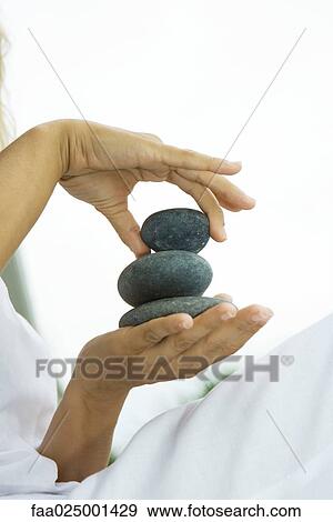 Stock Photo - Person stacking pebbles in hand, cropped view. Fotosearch