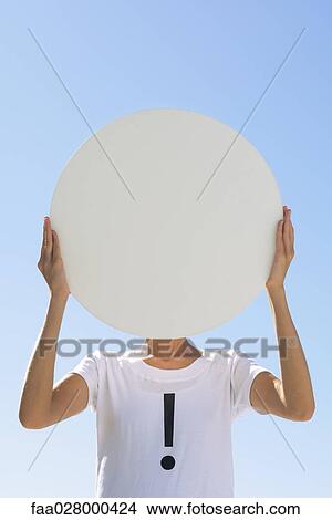 Person wearing tee-shirt printed with exclamation mark, holding large circle in front of face View Large Photo Image Picture - Person wearing tee-shirt printed with exclamation mark, holding large circle in front of face. Fotosearch