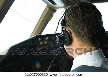 Stock Image - Pilot wearing headphones, rear view, close-up. Fotosearch