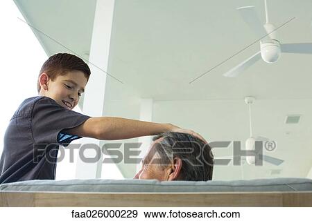 Preteen boy with hand on grandfather's head, both looking at each other, low angle view View Large Photo Image Stock Photo - Preteen boy with hand on grandfather's head, both looking at each other, low angle view. Fotosearch