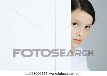 Preteen girl looking around corner of wall, cropped View Large Photo Image Picture - Preteen girl looking around corner of wall, cropped. Fotosearch