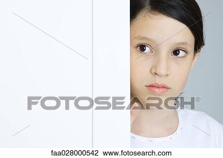 Preteen girl, looking around edge of wall, close-up View Large Photo Image Stock Image - Preteen girl, looking around edge of wall, close-up. Fotosearch