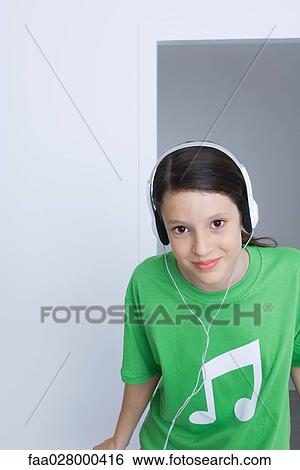 Preteen girl wearing tee-shirt printed with musical notes, listening to headphones, smiling View Large Photo Image Stock Photograph - Preteen girl wearing tee-shirt printed with musical notes, listening to headphones, smiling. Fotosearch