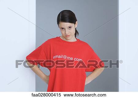 Stock Photography - Preteen girl wearing tee-shirt printed with e-mail address, hands on hips, looking at camera. Fotosearch