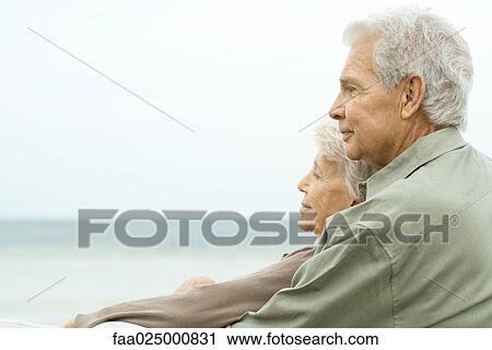 Stock Image - Senior couple outdoors, looking at view, side view. Fotosearch