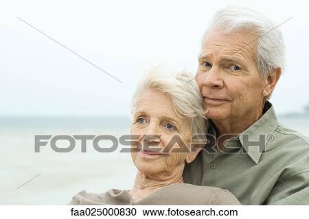 Stock Image - Senior couple together outdoors, man smiling at camera. Fotosearch