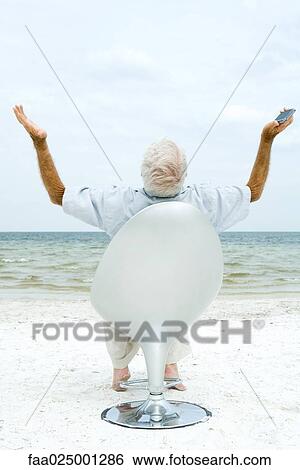 Senior man holding cell phone, arms up and head back, rear view View Large Photo Image Stock Photograph - Senior man holding cell phone, arms up and head back, rear view. Fotosearch