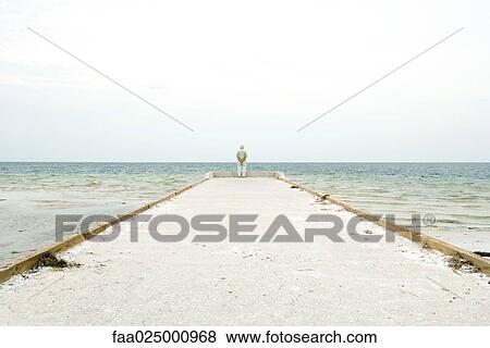 Senior man standing at end of pier, facing ocean, in distance, rear view View Large Photo Image Stock Photo - Senior man standing at end of pier, facing ocean, in distance, rear view. Fotosearch