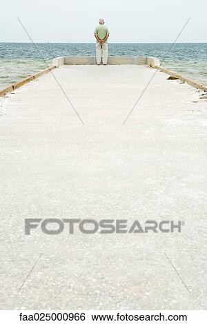 Senior man standing at end of pier, facing ocean, in distance, rear view View Large Photo Image Stock Photograph - Senior man standing at end of pier, facing ocean, in distance, rear view. Fotosearch