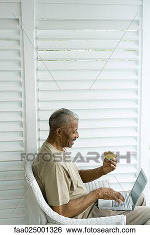 Senior man using laptop, making on-line purchase with credit card View Large Photo Image Stock Photograph - Senior man using laptop, making on-line purchase with credit card. Fotosearch
