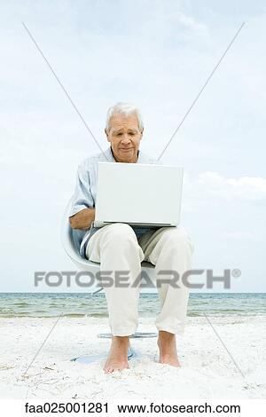 Senior man using laptop on beach View Large Photo Image Stock Image - Senior man using laptop on beach. Fotosearch