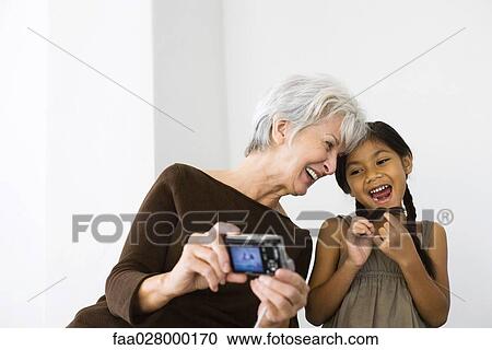 Senior woman photographing self and daughter with digital camera, both laughing View Large Photo Image Stock Image - Senior woman photographing self and daughter with digital camera, both laughing. Fotosearch