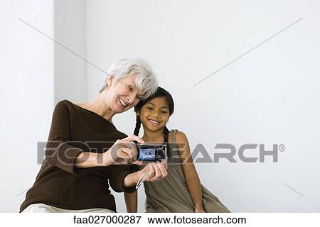 Senior woman photographing self and granddaughter with digital camera, both smiling View Large Photo Image Stock Photo - Senior woman photographing self and granddaughter with digital camera, both smiling. Fotosearch
