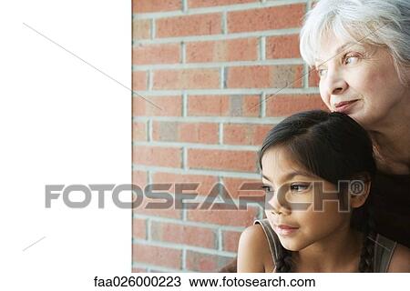 Senior woman resting her chin on granddaughter's head, both looking away, close-up View Large Photo Image Stock Image - Senior woman resting her chin on granddaughter's head, both looking away, close-up. Fotosearch