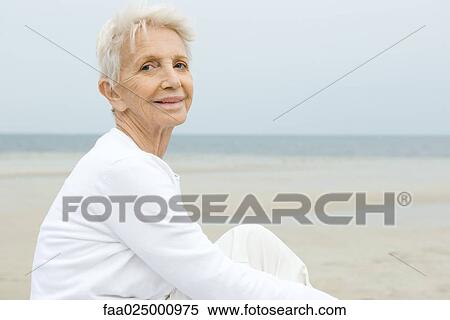 Stock Photography - Senior woman smiling, beach in background. Fotosearch