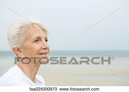 Senior woman smiling, looking away, beach in background View Large Photo Image Stock Image - Senior woman smiling, looking away, beach in background. Fotosearch