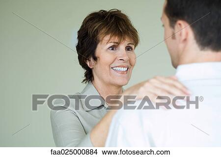 Senior woman standing in front of adult son with her hand on his shoulder, smiling View Large Photo Image Picture - Senior woman standing in front of adult son with her hand on his shoulder, smiling. Fotosearch