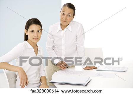 Senior woman with younger colleague in office, both smiling at camera View Large Photo Image Picture - Senior woman with younger colleague in office, both smiling at camera. Fotosearch