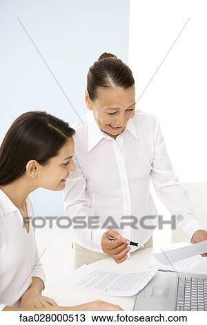 Senior woman working with younger colleague in office, smiling View Large Photo Image Stock Image - Senior woman working with younger colleague in office, smiling. Fotosearch