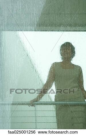 Stock Photograph - Silhouette of woman looking through window in rain. Fotosearch