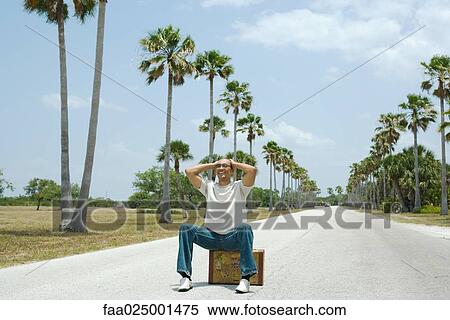 Stock Photography - sitting, suitcase, road, traveler, hitchhiker, on top of. Fotosearch