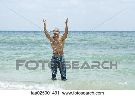 standing, splashing, getting wet, arms raised, ankle deep in water, at the beach View Large Photo Image Stock Image - standing, splashing, getting wet, arms raised, ankle deep in water, at the beach. Fotosearch