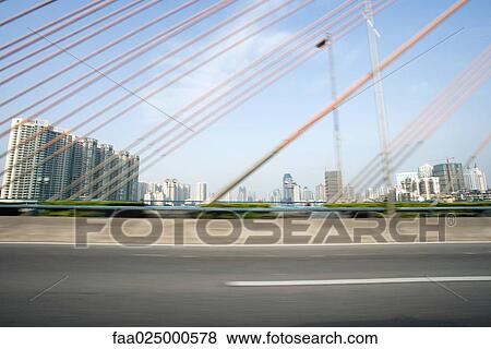 Suspension bridge, cropped view, cityscape in background View Large Photo Image Stock Photo - Suspension bridge, cropped view, cityscape in background. Fotosearch