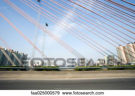Suspension bridge, cropped view, cityscape in background View Large Photo Image Stock Photo - Suspension bridge, cropped view, cityscape in background. Fotosearch