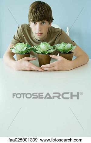 Teen boy holding arms around plants View Large Photo Image Stock Photo - Teen boy holding arms around plants. Fotosearch