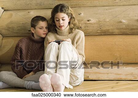 Teen girl and preteen boy sitting side by side, girl playing video game View Large Photo Image Stock Image - Teen girl and preteen boy sitting side by side, girl playing video game. Fotosearch