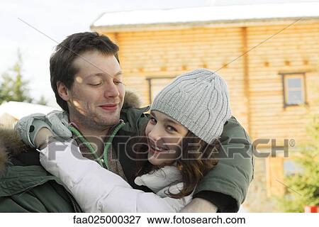 Stock Photo - Teen girl hugging young man, looking over shoulder at camera, laughing. Fotosearch