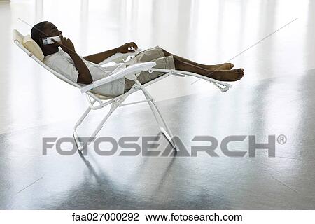 Teenage boy sitting in lounge chair, using cell phone, side view View Large Photo Image Stock Image - Teenage boy sitting in lounge chair, using cell phone, side view. Fotosearch