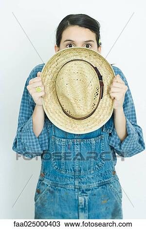Teenage girl hiding behind straw hat, looking at camera View Large Photo Image Stock Image - Teenage girl hiding behind straw hat, looking at camera. Fotosearch