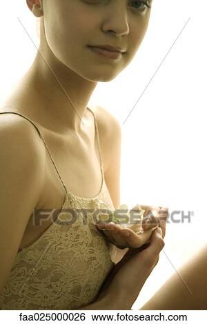 Teenage girl holding flower against chest, cropped view View Large Photo Image Stock Photograph - Teenage girl holding flower against chest, cropped view. Fotosearch