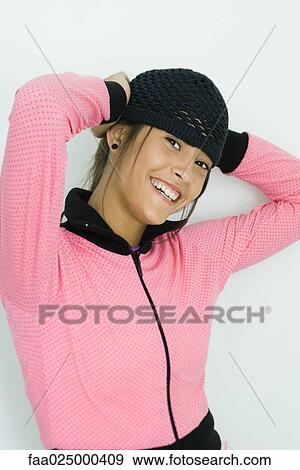 Teenage girl holding knit hat on head, smiling at camera, portrait View Large Photo Image Stock Photo - Teenage girl holding knit hat on head, smiling at camera, portrait. Fotosearch
