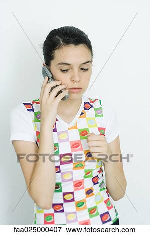 Teenage girl holding up cell phone, looking down View Large Photo Image Stock Photo - Teenage girl holding up cell phone, looking down. Fotosearch