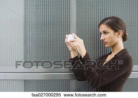 Teenage girl holding up digital camera, side view View Large Photo Image Stock Photography - Teenage girl holding up digital camera, side view. Fotosearch