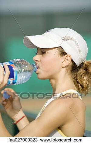 Teenage girl in cap drinking water from bottle, side view View Large Photo Image Stock Image - Teenage girl in cap drinking water from bottle, side view. Fotosearch