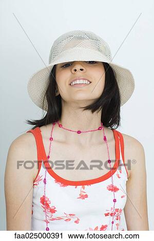 Teenage girl looking at camera from beneath hat, smiling, portrait View Large Photo Image Stock Image - Teenage girl looking at camera from beneath hat, smiling, portrait. Fotosearch