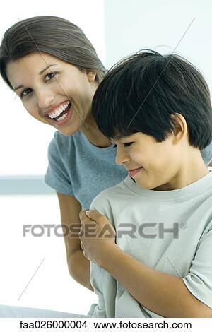 Teenage girl looking over boy's shoulder at camera, both smiling View Large Photo Image Picture - Teenage girl looking over boy's shoulder at camera, both smiling. Fotosearch