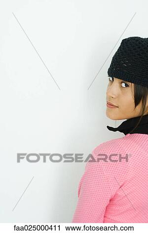 Stock Image - Teenage girl looking over shoulder at camera, cropped view. Fotosearch