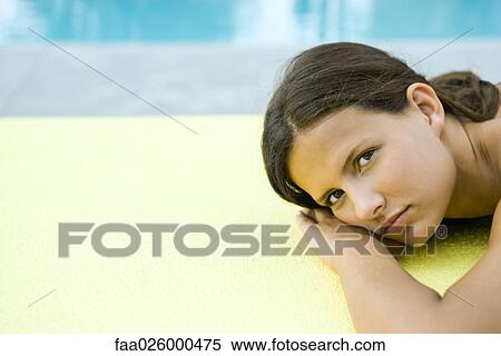 Teenage girl lying on stomach, head resting on arms, looking at camera View Large Photo Image Stock Photography - Teenage girl lying on stomach, head resting on arms, looking at camera. Fotosearch